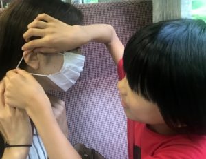 列車内でママにマスクをつける息子