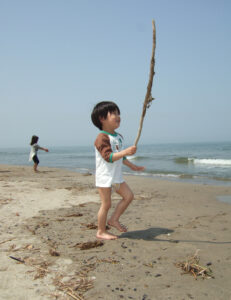 藤塚浜で流木を掲げる息子