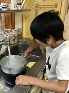 台所で鍋を洗う息子