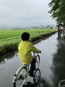 雨の中サイクリングロードを走る息子